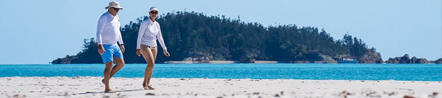 two people walking along a white sand beach