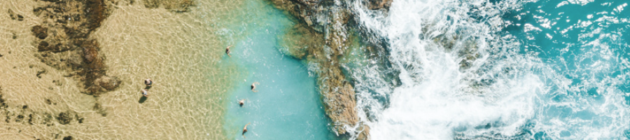 A birds eye view of a rock pool next to the ocean