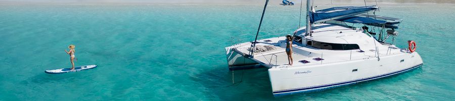 Whitsunday Blue catamaran at whitehaven beach with girl paddleboarding