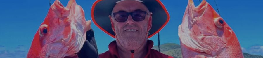 man holding up two fish on a fishing tour whitsundays