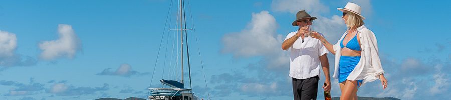 Whitsunday Blue three day, three night sailing tour Couple walking along the water cheersing their glasses