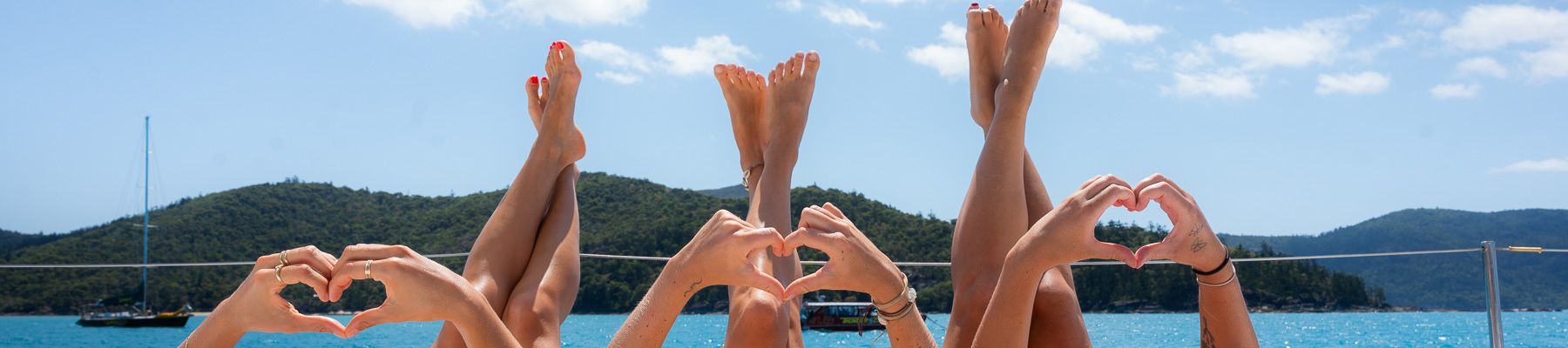 Three women on a boat with their hands in the shape of hearts