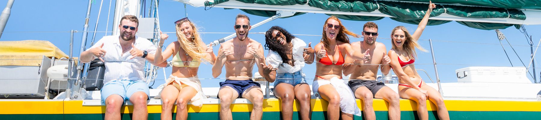 A group of friend sitting on the edge of a sailing yacht