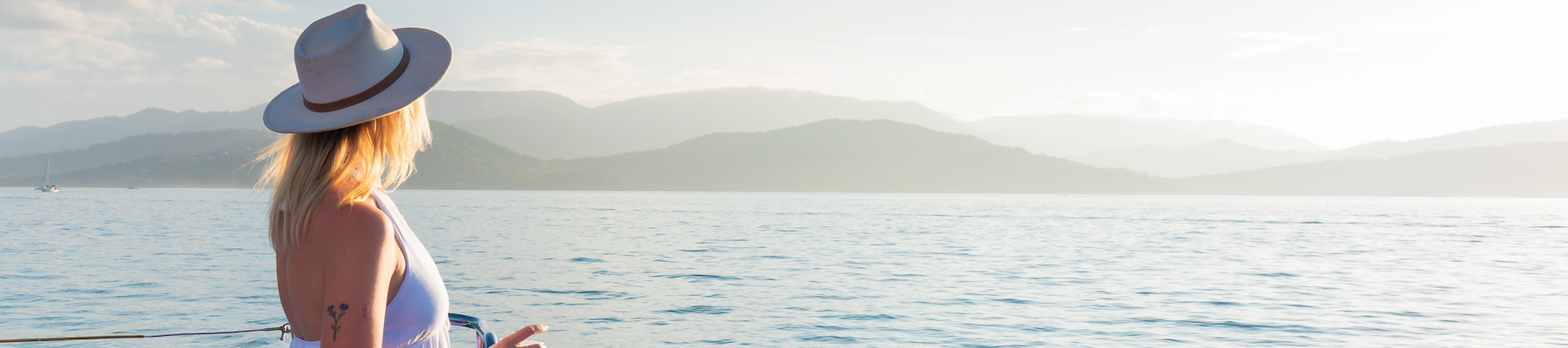 Camira Sunset Private Charter A woman in a white hat standing on a boat looking at the sunset
