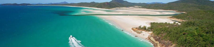 A boat cruising past an island with a white sand beach