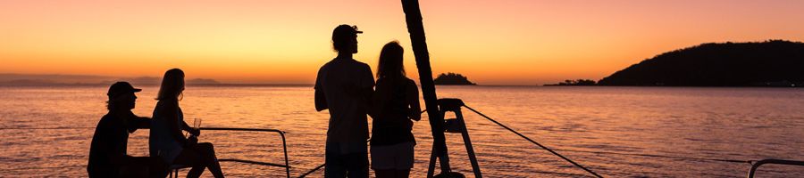 Whitsunday Getaway three day, three night sailing tour People onboard Whitsunday Getaway enjoying a drink on the foredeck as the sun sets