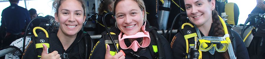 three scuba divers onboard the vessel preparing to dive