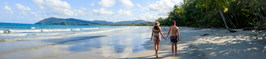 couple holding hands walking on daintree rainforest beach
