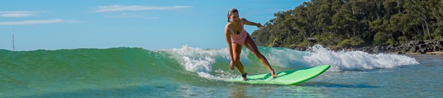 Surfing Noosa girl surfing in the turquoise ocean around noosa