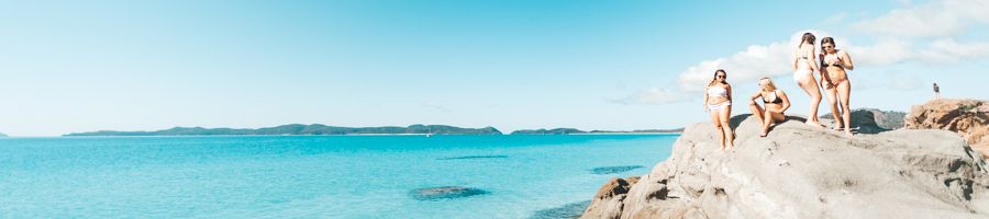 People sitting on the rocky outcrop of Bettys Beach, Whitsundays