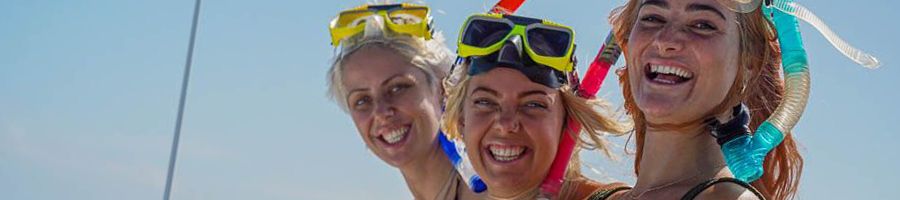 three people smiling with snorkel gear on a boat