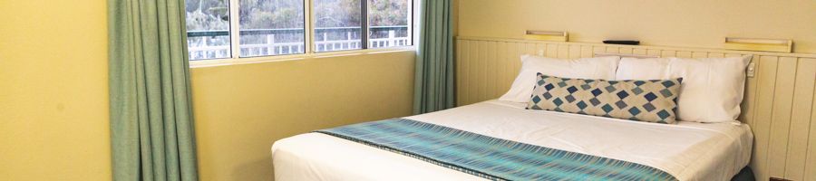 bed in a hotel room with a window and yellow walls