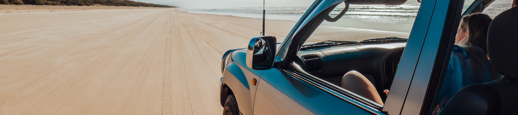 a four wheeled drive driving along the sand on a beach
