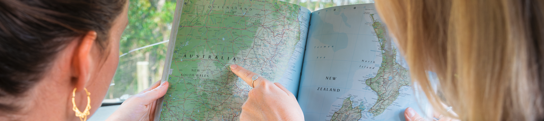 two women in a car pointing to a map of australia