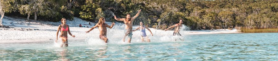 Group of young travellers running into Lake Mackenzie