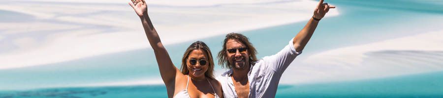 Milady Charter two people standing at a lookout with their arms in the air