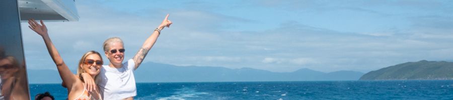 Great Barrier Reef Tour two girls smiling on the edge of a boat on the reef