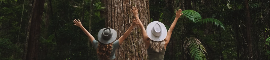 Central Station Two girls wearing hats throwing their arms in the air in a rainforest