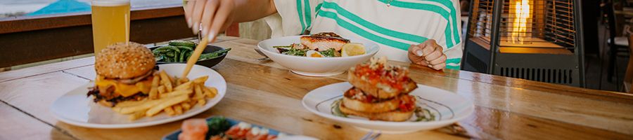 Four plates of Northerlies menu food - burgers, salads and beer