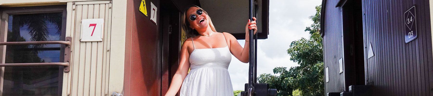 A woman standing on a train smiling at the camera