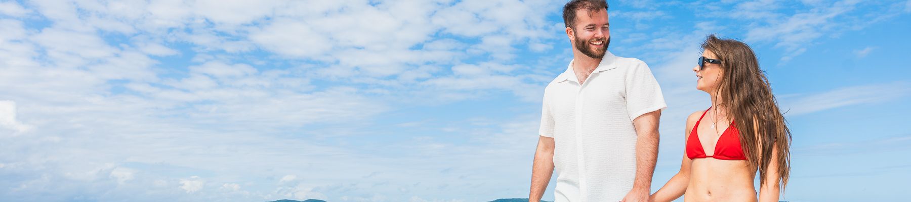 A man and woman walking hand in hand along a beach