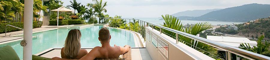 Airlie Searene Apartments couple lounging by resort pool in Airlie Beach