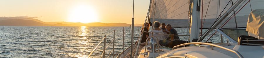 Sunset behind the horizon while people sit on a sailboat