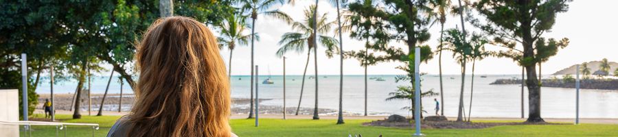 Airlie Beach girl looking at palm trees on airlie beach foreshore