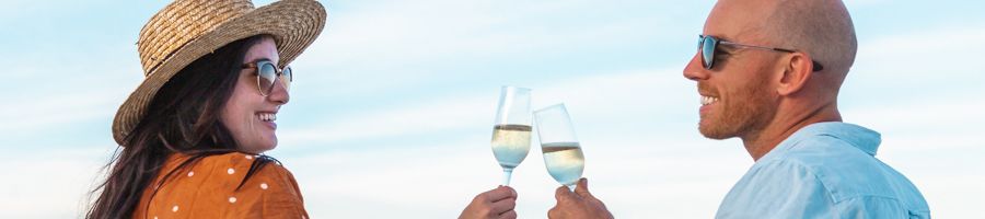 Two people cheersing glasses of champagne on the Beach