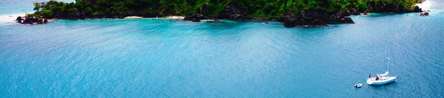 Domino Langford Island sailing Domina Private Day Sail Boat in blue waters near a lush green island