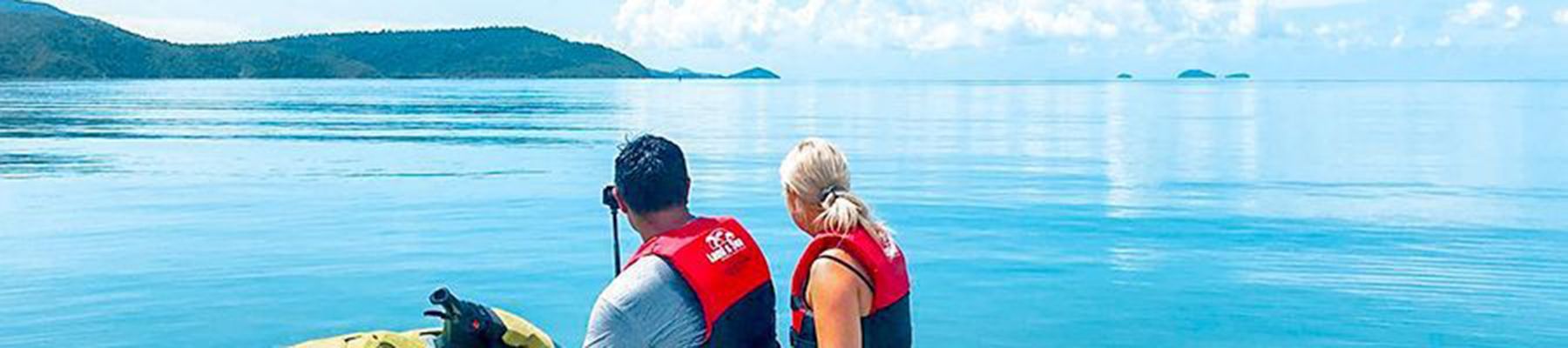 Couple on a jetski looking at the calm, crystal water