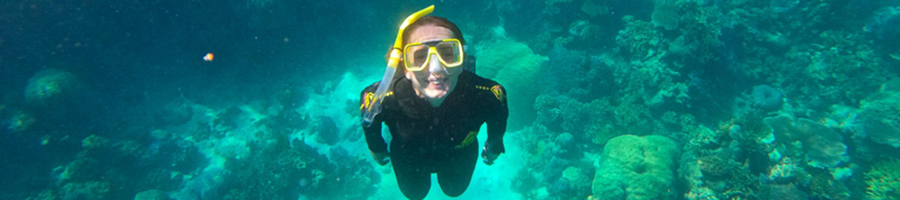 Girl with black wetsuits in the reef
