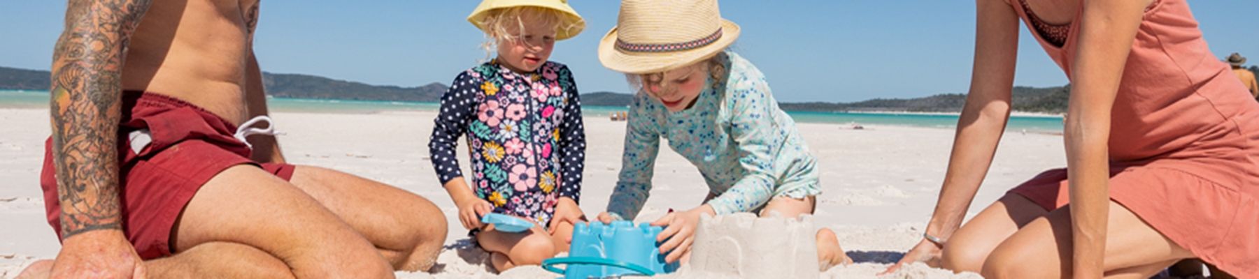 A family playing in the white sands of Nudey Beach