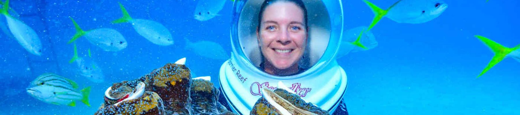 Woman helmet diving in the Great Barrier Reef with fish