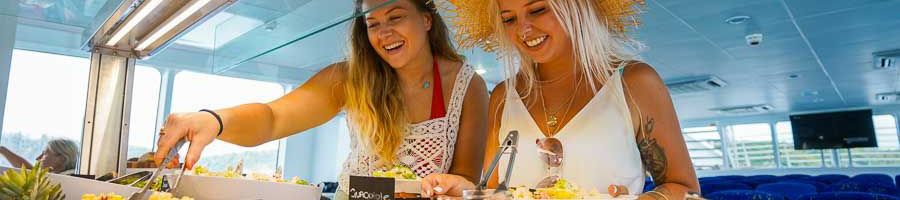 Two women serving themselves food from a buffet 
