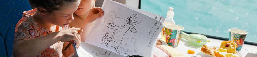 Family friendly tours, Purely Whitehaven Half-Day Tour Two children using a colouring in book inside the Sealink cruise