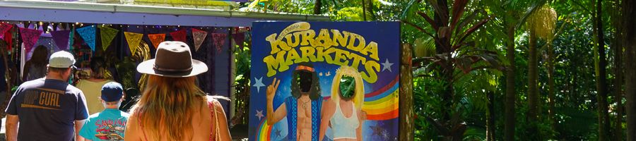 Family walking into Kuranda Markets with colourful flags