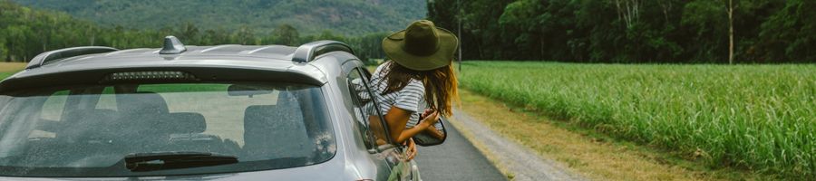 Woman with her head out of the car in greenery
