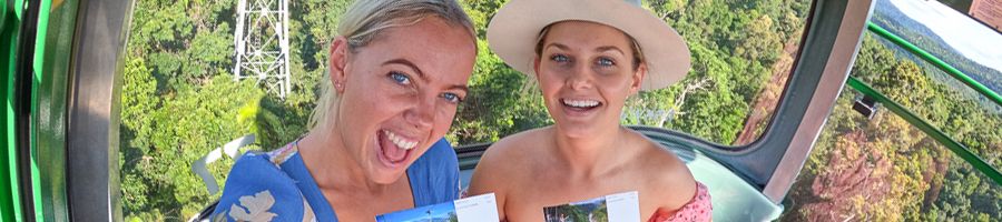 Two people in a cable car holding tickets and smiling