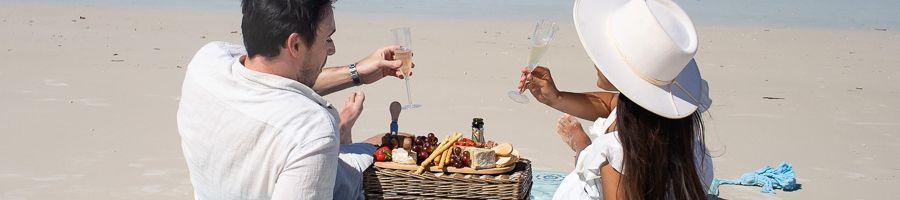 Beach Picnic Whitsundays couple having a picnic with champagne on the beach