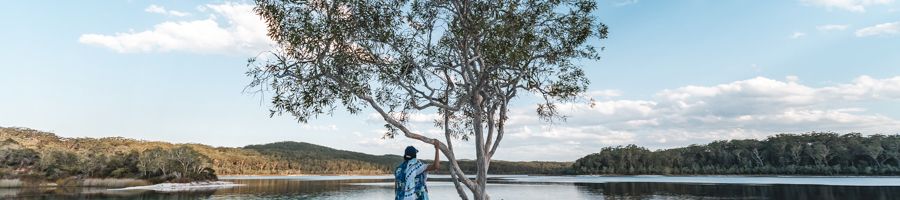 Lake McKenzie girl standing near a tree at Lake McKenzie on K'gari