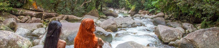 girls sitting in front of a waterfall in the rainforest