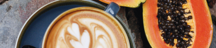 Cup of coffee and papaya cut in half flat lay