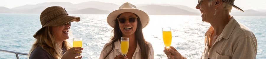 people smiling and drinking cocktails on a ship