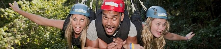 A man and two women linking arms and smiling on the Giant Swing at AJ Hackett's Skypark in Cairns