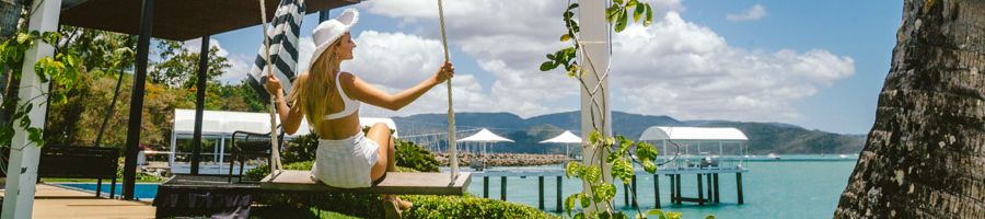 Coral Sea Marina A woman on a swing by the water in a resort