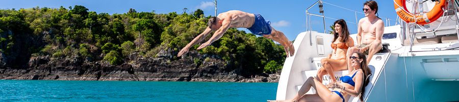 Whitsunday Pearl Catamaran A man diving off a catamaran while others watch and smile