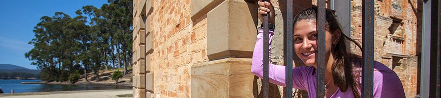 Port Arthur Historical Site Tourism, Tasmania A woman in a pink shirt holding onto the bars of old prison