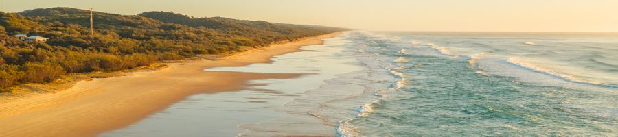 sunrise over the blue ocean and golden sands of 75 mile beach k'gari