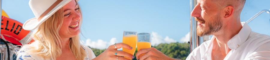 Whitsunday Pearl Menu A man and woman holding up champagne glasses on a boat